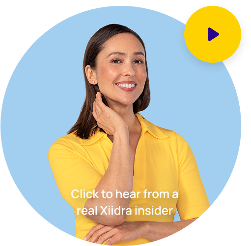 Woman in a yellow shirt with brown hair smiling with here hand by her chin