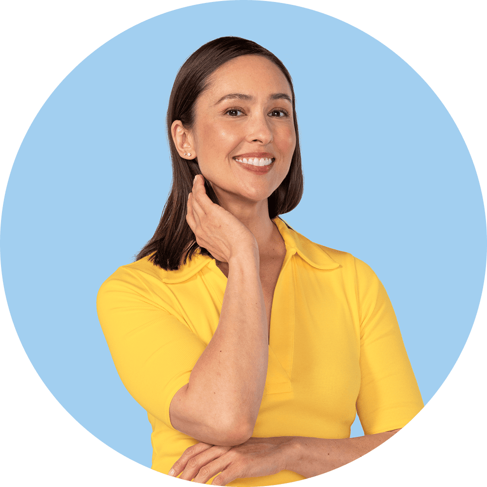 Woman in a yellow shirt with brown hair smiling with here hand by her chin