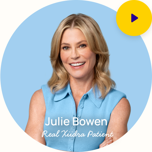 Julie Bowen looking smiling at the camera with the words "Julie Bowen real Xiidra patient" at the bottom and a play button in the top right corner