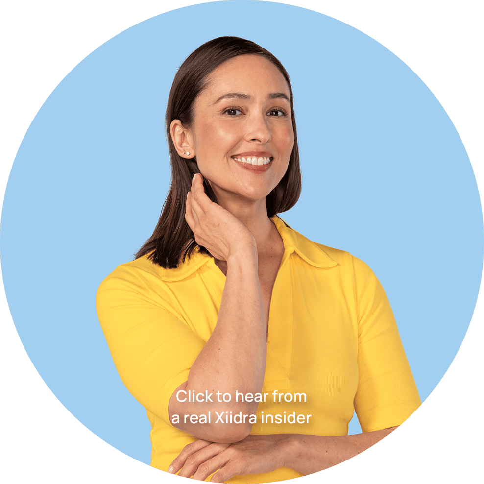 Woman in a yellow shirt with brown hair smiling with here hand by her chin