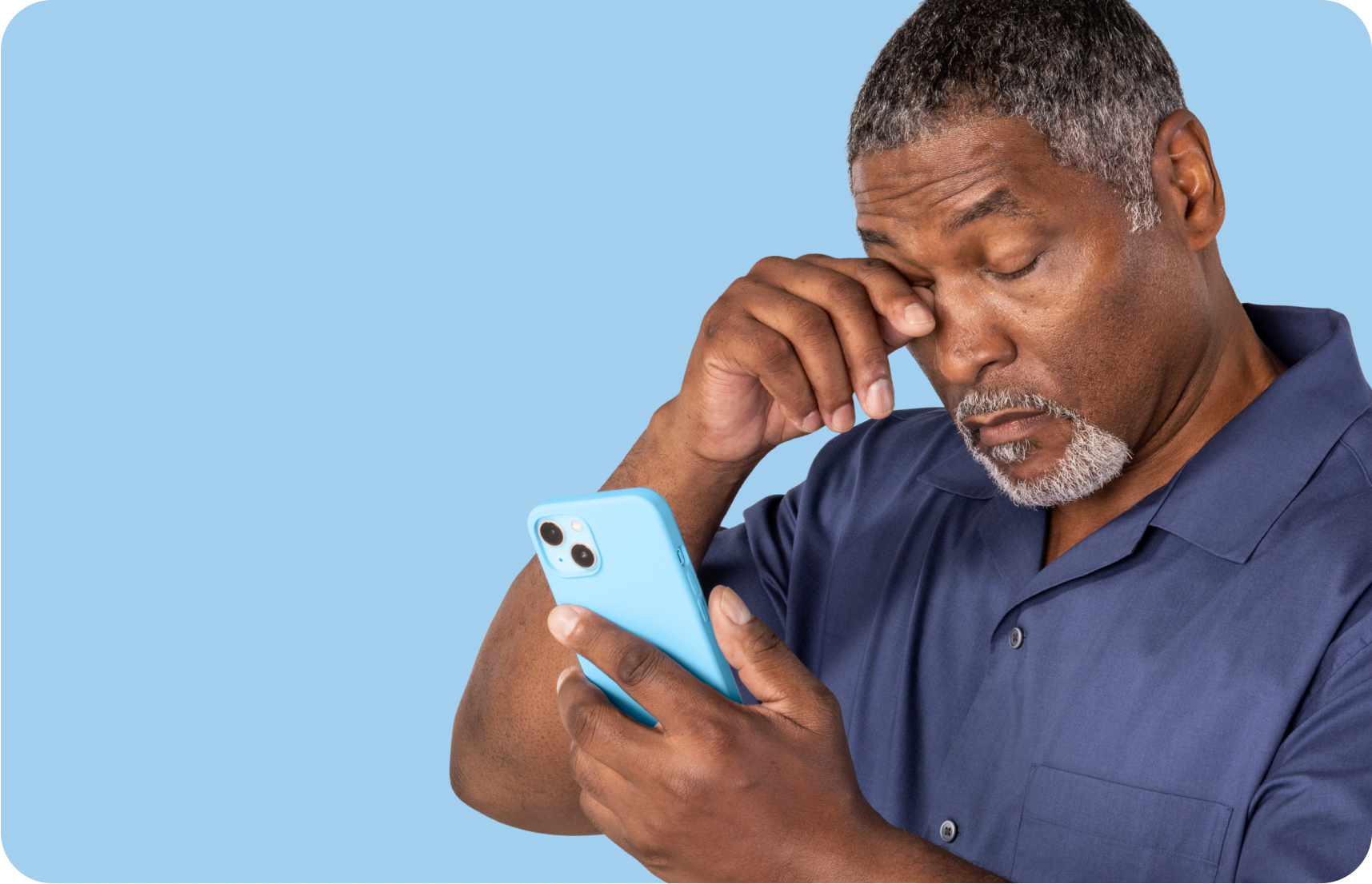 An older man looking at his phone rubbing his eyes